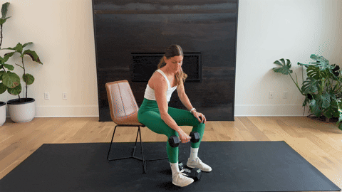 woman performing a palm down wrist curl with a dumbbell as part of the best forearm exercises