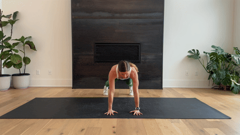 woman performing a bodyweight plank and shoulder tap as part of the best forearm exercises