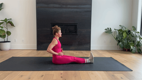 woman performing a seated double leg hamstring stretch as part of the best hamstring exercises