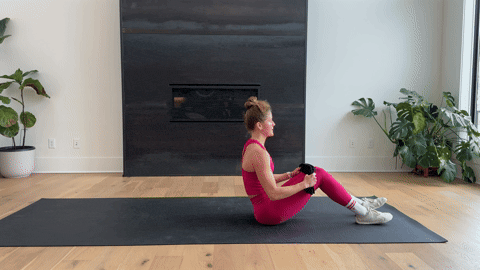 woman performing a lying single leg towel stretch as part of the best hamstring exercises