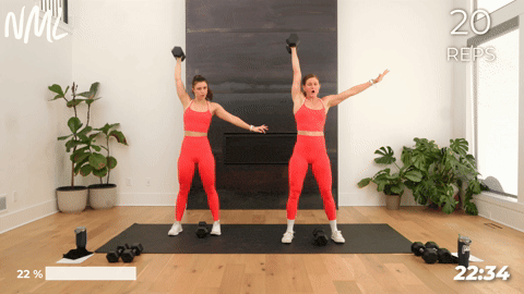 two women performing a dumbbell snatch and press in a full body workout routine