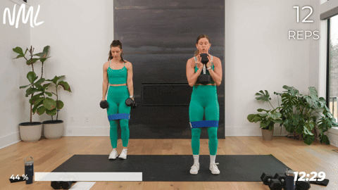 two women performing a banded side to side squat in a leg and glute workout