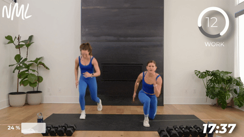 two women performing lunge jumps with dumbbells.