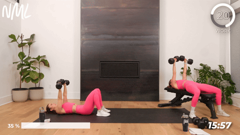 two women performing an alternating chest press with dumbbells in a leg and chest workout