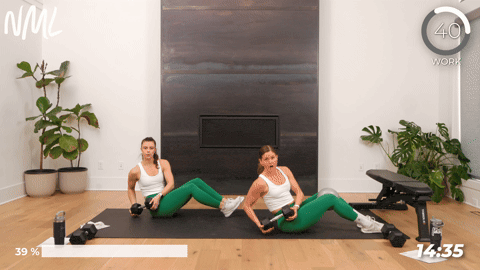 two women performing a seated dumbbell twist in a core workout