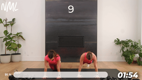 two women performing push ups on a mat.