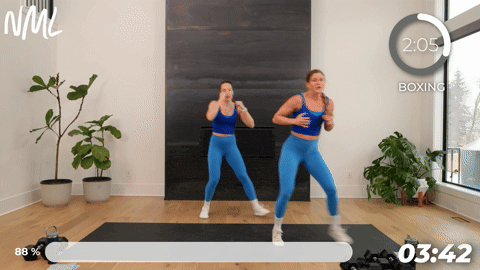 two women performing a shuffle and crossbody punch in a boxing workout at home