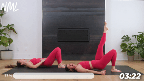 two women performing a single leg glute bridge in a mat pilates workout