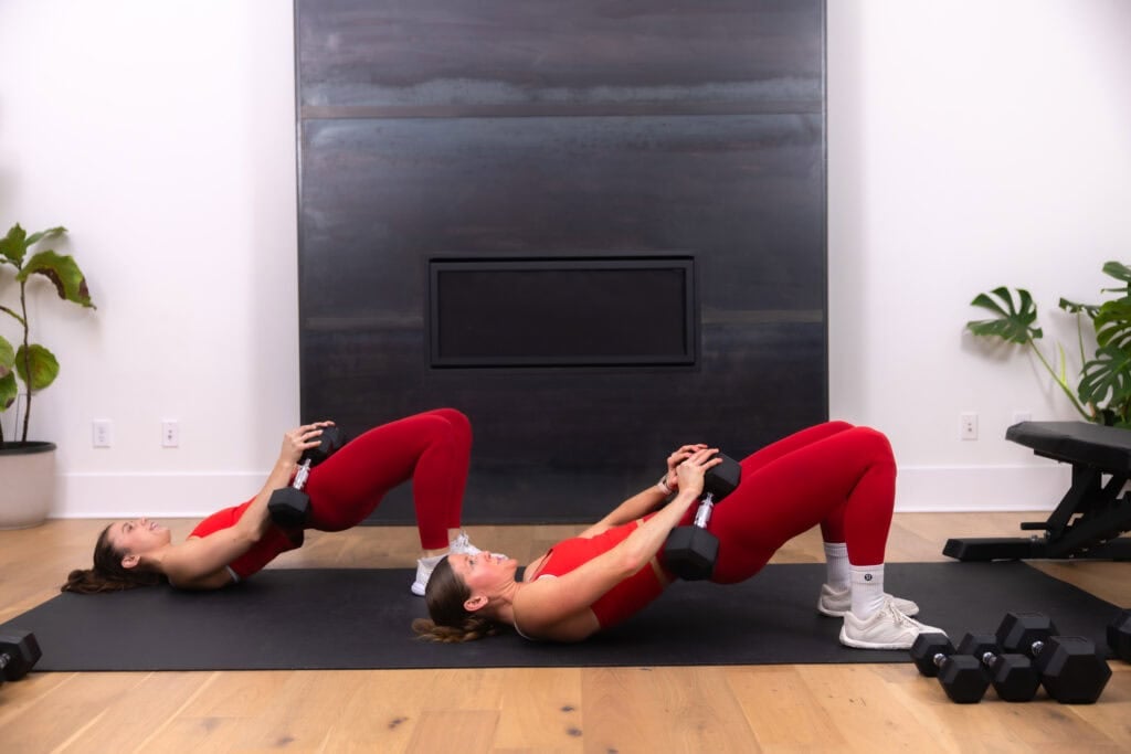 two women performing a dumbbell glute bridge in a lower body workout