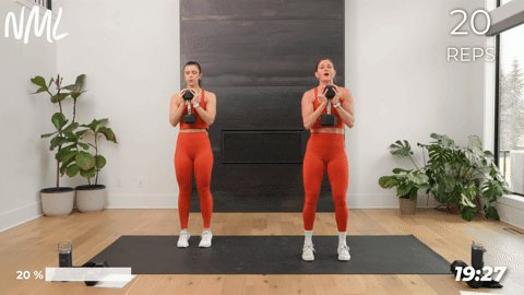 Two women doing calf raises and holding a dumbbell at their chest as part of a core and calf workout. 