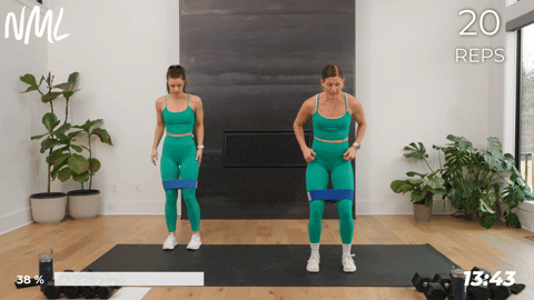 two women performing a banded side to side squat in a leg and glute workout