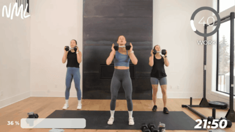 3 standing women performing an overhead press with one dumbbell as part of marine style workout