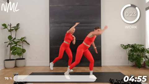 two women performing alternating standing crunches in a walking workout