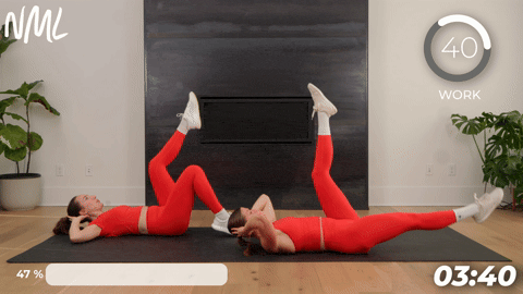 two women performing alternating scissor kicks in a quick ab workout