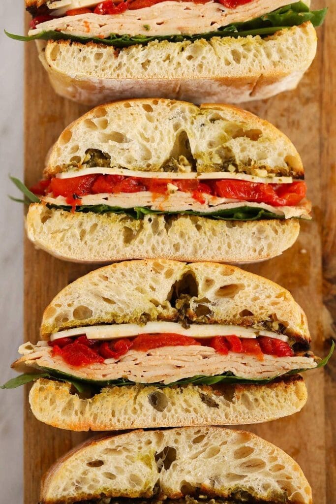 Turkey Pesto Sandwiches with turkey, tomato, pesto, greens, cheese and bread.