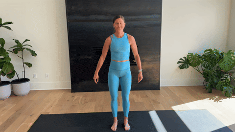 A woman in a blue workout outfit doing cross-body triceps stretches.