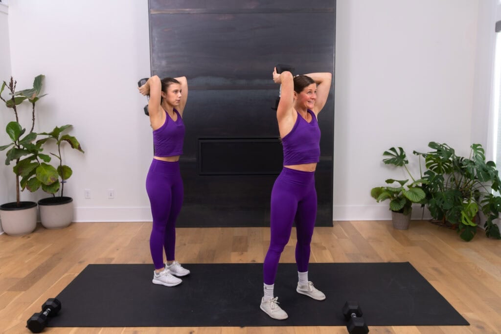 two woman doing an overhead tricep workout with dumbbells