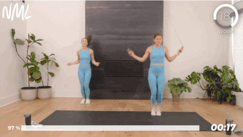 Two woman working out doing reverse jumps with a jump rope.
