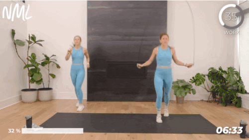 Two woman working out doing ski jumps with a jump rope.